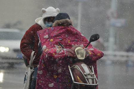 A resident wearing a winter jacket rides with a passenger in the snow in Fuyang.
Temperatures drop to -8 C in the Fuyang. China's meteorological authority issued an alert for a cold wave as a strong cold front will sweep across most parts of Central and East China.