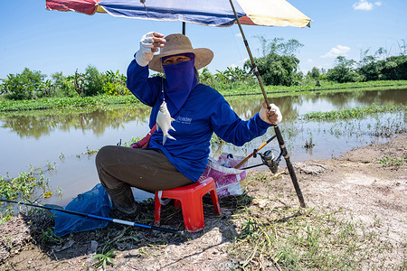 A Thai woman seen holding a Pla Kra-Mang, a popular species of local fish found in the Lower Songkhram River basin and Mekong wetlands. It is a traditional ingredient in Thai Isan food culture and cuisine. Artisanal fishing is a traditional and sustainable part of daily life in the northern Udon Thani province.