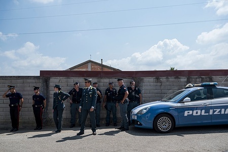 Policemen seen standing near the new houses in Rosarno. Italian government officials oversaw the start of dismantling the San Ferdinando tent city, relocating around 100 migrant farm workers to newly redeveloped housing in Rosarno's Serricelle district. The operation marks a major government effort to replace the long-standing settlement, which had become a symbol of poor living conditions, labor exploitation, and public health concerns.