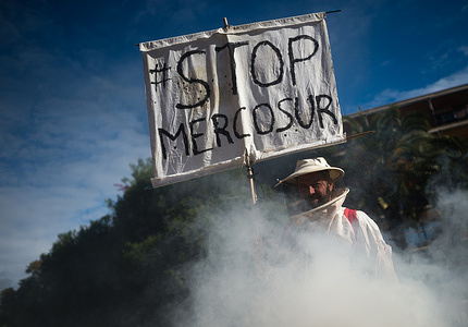 A beekeeper is seen holding a placard between smoke as he takes part in a protest against the EU-Mercosur free trade agreement. Farmers across Spain are called to participate in a nationwide demonstrations in support of rural environment. The EU-Mercosur free trade agreement suppose a danger to Spain rural and budget reduction of the Common Agricultural Policy.