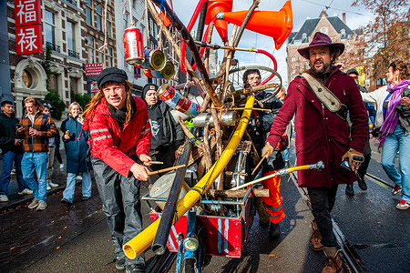 People are seen playing homemade instruments placed on a bike. ADEV (Amsterdam Danst Ergens Voor), in English 'Amsterdam Dances For A Cause', organized for the 13th time its annual demonstration for squatting, free spaces, and affordable housing in the city. People danced, accompanied by large trucks and loud music systems, to reclaim more free spaces in the city.