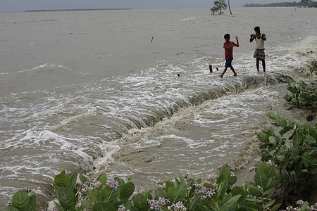 People walk on the embankment after the Cyclone Yaas effect at the coastal area of Patharghata in Barguna.
At least two deaths were reported Wednesday as Cyclone Yaas triggered storms and floods in the coastal areas of Bangladesh.
