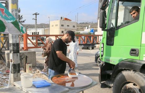 A Palestinian man sells sweets in front of the closed iron gate at the Deir Sharaf checkpoint. Israeli forces closed the iron gate at the Deir Sharaf military checkpoint west of Nablus, restricting movement between Palestinian Authority-administered areas. Israeli military authorities implemented the lockdown as part of heightened security measures across the West Bank, blocking a major arterial road linking Nablus to neighboring governorates.