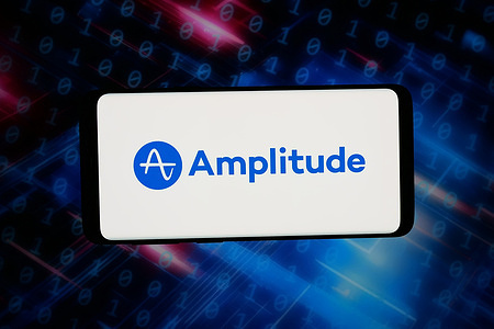In this photo illustration, the logo of US analytics software company Amplitude Inc. is displayed on a smartphone in front of abstract background on computer screen.