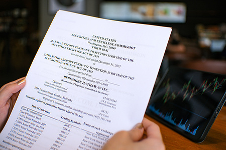 In this photo illustration, a woman is reviewing the Form 10-K annual report of Berkshire Hathaway Inc. for the fiscal year ended December 31, 2025.