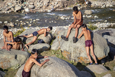 Kashmiri boys rest on rocks after bathing in a stream on a sunny day in Budgam district, south-west of Srinagar.