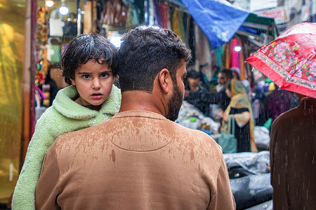 Kashmiri man carrying his child arrive for shopping during a rainfall ahead of the Muslim festival Eid-al-Fitr at a local market in Srinagar. Markets across the Muslim world witness huge shopping rush in preparation for Eid al-Fitr, a celebration that marks the end of the Muslim fasting month of Ramadan.