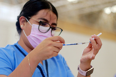 A nurse holds the vaccination syringe and a vial of the Pfizer vaccine at a vaccination center.The health authorities are carrying out a vaccination day for ages between 50 to 59 years old at the Ecocentro Expositor facilities. In addition, other groups such as pregnant women as well as dentists and some private doctors were cited.