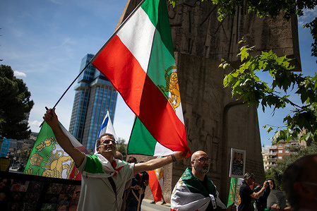 A protester carries an Iranian flag during the demonstration. Iranian residents gathered outside the Norwegian embassy in Madrid to demand an end to European support for the Ayatollahs' theocratic regime.