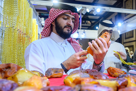 A customer checks the quality of raw amber at a stall during the Katara International Exhibition for Kahraman, featuring artwork and handicrafts made with amber, at Katara Cultural Village in Doha