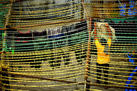 A worker hangs out washing in Dhobi Ghat, a large open air laundry site in Mumbai, India. Dhobi Ghat, an open air laundry space, with residential and commercial buildings in the background in the Mahalaxmi area of Mumbai, India