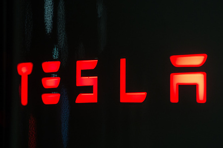 In this photo illustration, the Tesla logo is seen on a Tesla Supercharger rapid battery charging station. Tesla, Inc. is an American automotive and energy company that specialises in electric car manufacturing.