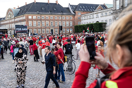 A woman uses her mobile phone during a demonstration at Christiansborg Palace Square in Copenhagen. Hundreds of protesters gathered in solidarity with Palestinians in Gaza, forming a symbolic 'red line for Gaza' human chain. The demonstration was organized by Amnesty International Denmark, Save the Children, DanChurchAid, International Media Support, Oxfam, Greenpeace, and ActionAid.