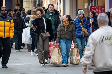 Two women seen carrying shopping bags. Shoppers crowded Oxford Street as post Christmas Boxing Day and Winter Sales drew large numbers of people to central London, with major retailers offering heavy discounts. The scenes reflected the annual surge in footfall as consumers took advantage of seasonal promotions during one of the busiest retail days of the year.