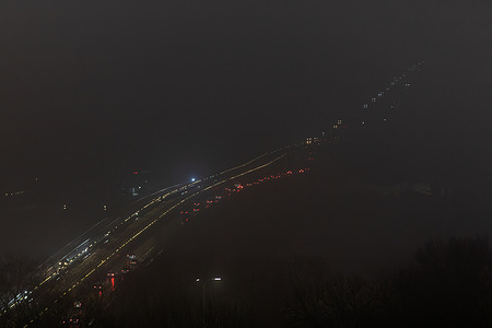 Vehicles are seen traversing a highway in Kyiv, Ukraine, their headlights providing the only illumination amidst a massive power outage Kyiv’s energy system remains in a critical state due to a severe power deficit that cannot be covered by domestic generation or imports. The situation is exacerbated by freezing temperatures and a lack of central heating in many residential areas, forcing residents to rely on electric heaters; this overloads the damaged grid and triggers further emergency outages. Despite around-the-clock efforts by repair crews, the systemic energy shortage remains massive, compelling the capital to operate under strict electricity restrictions and rely heavily on "Points of Invincibility".