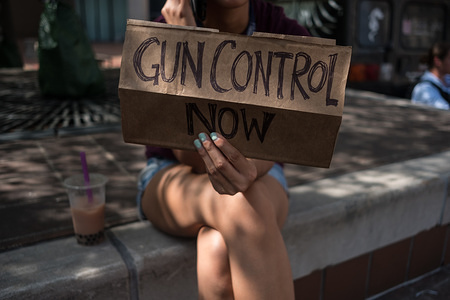 A woman holds a placard that say gun control now during a gun reform rally that was held in Dayton, Ohio in the wake of a mass shooting at the area earlier this month that left 9 dead and 27 wounded.