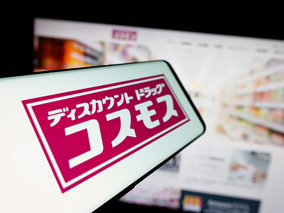In this photo illustration, a smartphone with the logo of Japanese company COSMOS Pharmaceutical Corp. is seen on screen in front of website.