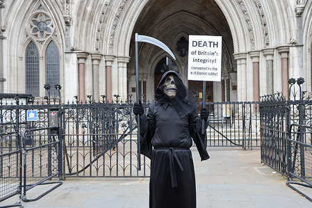 A supporter of Palestine Action wearing a mask holds a placard expressing opinion during a demonstration outside the Royal Courts of Justice as the government appeals the high court ruling that the ban on the activist group Palestine Action is unlawful.