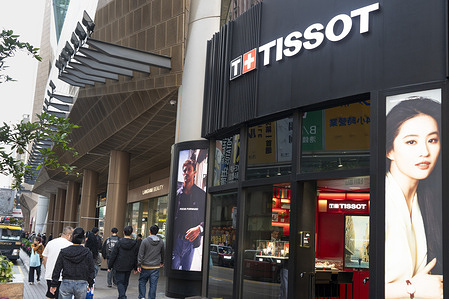 Pedestrians and shoppers walk past the Swiss luxury watchmaker Tissot store in Hong Kong.