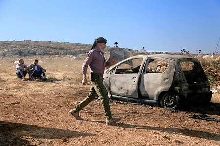 Palestinians inspect a burned-out car after an attack by Jewish settlers on a Palestinian family's home, where they also spray-painted Hebrew graffiti in the village of Beita, south of Nablus in the West Bank. Palestinian families facing home break-ins, property damage, and physical attacks by Israeli settlers say Prime Minister Benjamin Netanyahu's description of the perpetrators as a "handful of rioters" downplays the seriousness of the violence. Although Netanyahu condemned the attacks as criminal acts, critics say Palestinian communities continue to receive little protection and face ongoing violence and displacement.