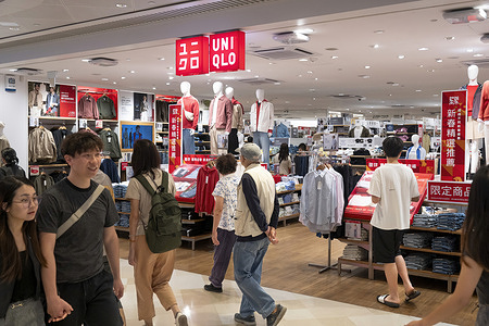Shoppers walk past the Japanese clothing brand Uniqlo logo and store in Hong Kong.