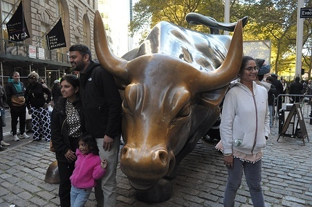 People take photos by the "Charging Bull" statue in the Financial District in Manhattan, New York City.