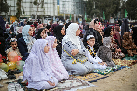 A Palestinian boy sits near his mother as they wait attend Eid Al-Fitr prayers at the Al Saraya area in central Gaza City. The Palestinian Ministry of Awqaf and Religious Affairs organized Eid prayers on the first day of Eid Al-Fitr in Al Saraya Square in the center of Gaza City, in which hundreds of worshipers participated. The first day of Eid al-Fitr marks the end of the holy fasting month of Ramadan.