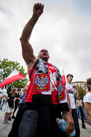 An anti-immigration protester gestures towards the Polish Parliament. On the afternoon of Saturday, far-right groups the All-Polish Youth and the Independence March gathered outside the European Parliament offices marching under the banner, "Poland for Poles, Poles for Poland". Across the street, antifascist demonstrators congregated to protest the gathering and the racist, anti-immigration sentiments expressed.