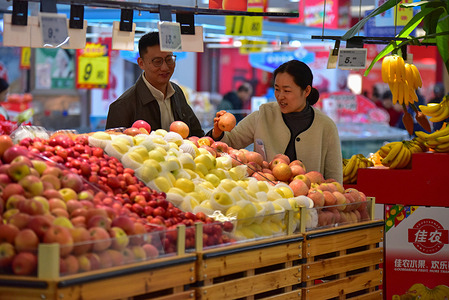 A man and a woman looking at apples in the fresh fruit area of RT-Mart supermarket.