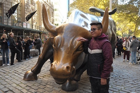 A person takes photos by the "Charging Bull" statue in the Financial District in Manhattan, New York City.