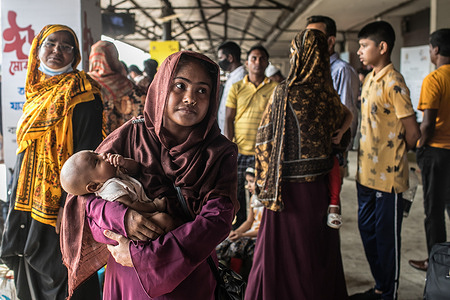 A woman carrying her child waits on a platform to board a train at Dhaka Airport Railway Station. People returning home to celebrate Eid al-Fitr festival, which marks the end of Islam's Holy fasting month of Ramadan.