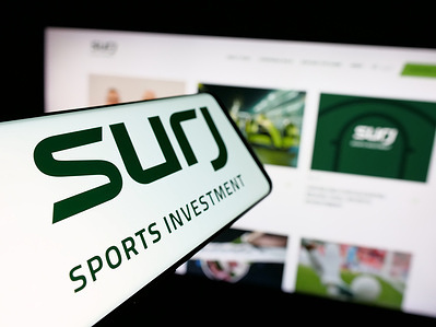 In this photo illustration, a smartphone with the logo of Saudi business SURJ Sports Investment Company is seen on screen in front of website.
