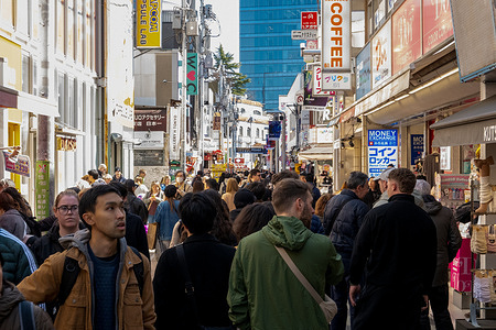 Pedestrians walk along the busy shopping street of Takeshita Street. Takeshita Street in Harajuku, Tokyo is a narrow, pedestrian shopping street known for its colorful youth fashion, quirky boutiques, and street food stalls. It’s a cultural hub for Japan’s teen fashion scene, drawing crowds with its vibrant energy and constantly evolving trends.