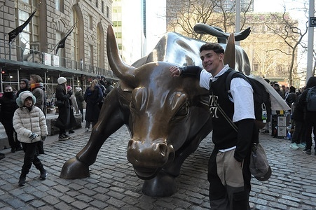 People take photos by the "Charging Bull" statue in the Financial District in Manhattan, New York City.