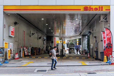 A man walks past a Shell gas station in Hong Kong, home to one of the world’s largest energy companies. Shell is reportedly weighing the merits of a potential takeover of rival BP, following a sharp drop in BP’s market value. While no formal offer has been made, the move, if pursued, could reshape the global energy landscape and face intense regulatory scrutiny.