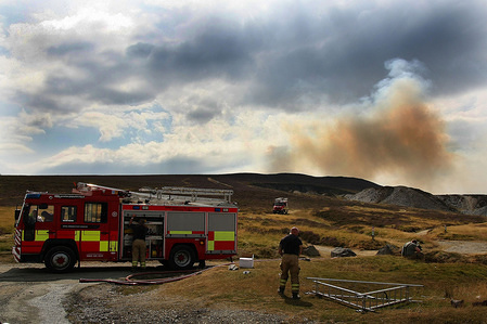 Fire Crews seen transferring water and equipment from a standard unit as smoke billows over the mountains above horseshoe pass in northeast Wales. 
There have been a number of fire recently caused by a combination of extreme heatwave weather conditions and the criminal acts of arsonists.