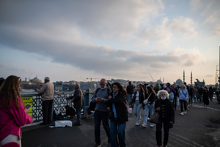 People seen walking on the Galata Bridge in Istanbul in the evening.