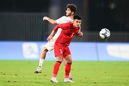 Seyedaria Barzegar (back) of the Islamic Republic of Iran men football team and le Nguyen Hoang (front) of the Vietnam men football team are seen in action during the 19th Asian Games men's football group round Group B match between Islamic Republic of Iran and Vietnam held at the Linping Sports Centre Stadium. Final score Islamic Republic of Iran 4:0 Vietnam.