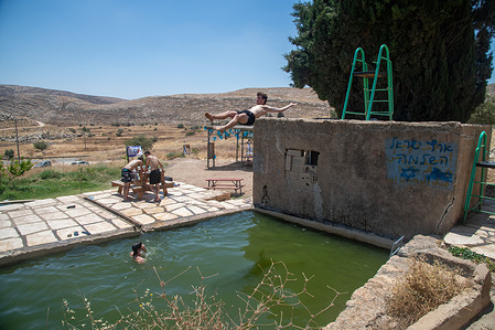 An Israeli teenager jumps into a swimming pool near Israeli settlements in Jordan valley.