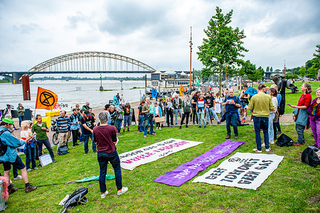 Climate activists seen listening to speeches during the rally. Activists from Extinction Rebellion protested for the second time against the new gas power plant that might be built on the site where a coal-fired power station was closed just a few years ago. At the same time, other XR activists blocked the 'De Oversteek bridge' as a protest against this new gas power plant.