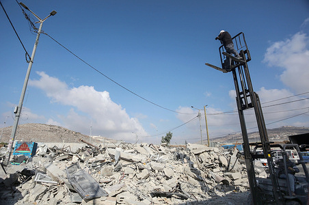 A photojournalist takes photos of the destruction with a crane after Israeli army bulldozers demolished a market in the West Bank village of Beita, near Nablus. Israeli military forces demolished the Beta Fruit and Vegetable Market, which was built near a settlement road owned by Jewish settlers.