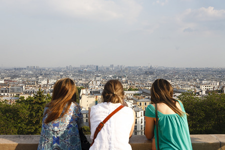 A trio of women look out over the rooftops of Paris from Montmarte hill.