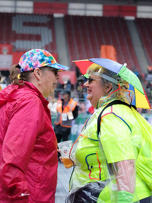 Festival goers wearing rain jackets and hat umbrella attend the Let's Rock Festival at St Mary's Stadium.
