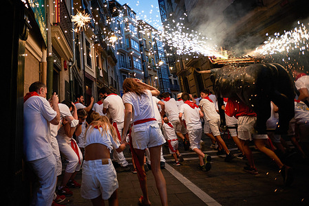 People run behind the fire bull during the San Fermín festivities. A man carrying a bull-shaped structure loaded with fireworks called Toro de Fuego (fire bull) shoots fireworks and runs through the streets of the Old Town of Pamplona during the San Fermín festivities.