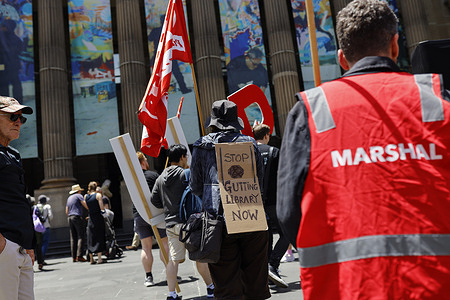 A protester is seen outside State Library Victoria during the demonstration. Protesters gathered outside State Library Victoria to oppose proposed operational changes that would significantly reduce reference library staff and shift core services toward self-service and digital systems. Organisers argue the changes would undermine essential public services and cannot be replaced by technology or AI. The rally called on the Minister and the library’s executive leadership to halt the plans and hold a public meeting to allow community input into the future of the library.