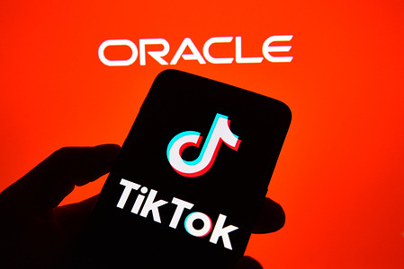 In this photo illustration a TikTok logo is seen displayed on a smartphone with an Oracle logo on the background.