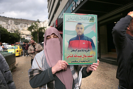A veiled mother of a prisoner holds up pictures of her son, who is imprisoned in Israeli jails, during a demonstration demanding his release from Israeli prisons in downtown Nablus in the West Bank.