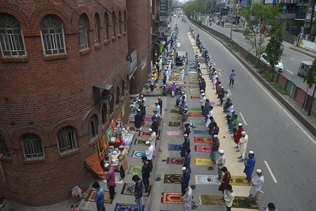 Muslims perform Jumma Namaz in an open road in front of a mosque as the mosque fills up after the Lockdown due to the Coronavirus was eased in Dhaka.
