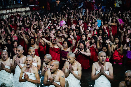 Nepalese Hindu priests and women devotees pray before taking a holy bath on the first day of the month-long Swasthani Bratakatha festival, devoted to Lord Madhav Narayan on the banks of the Salinadi river at Sankhu in Kathmandu.
