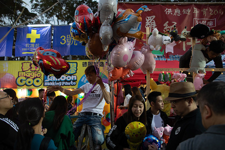 Stall owner sells pig-related balloons and toys in celebration of the year of the Pig in the Chinese Zodiac. The annual Chinese New Year market at Victoria Park, where locals shop for flowers and novelty toys in preparation for the three-day Chinese New Year celebration.